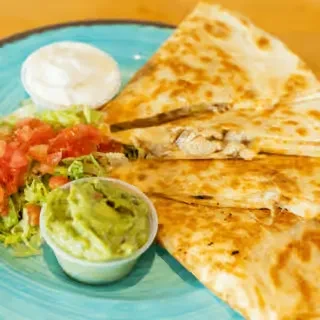 Golden brown chicken quesadilla with guacamole, sour cream, and pico de gallo.