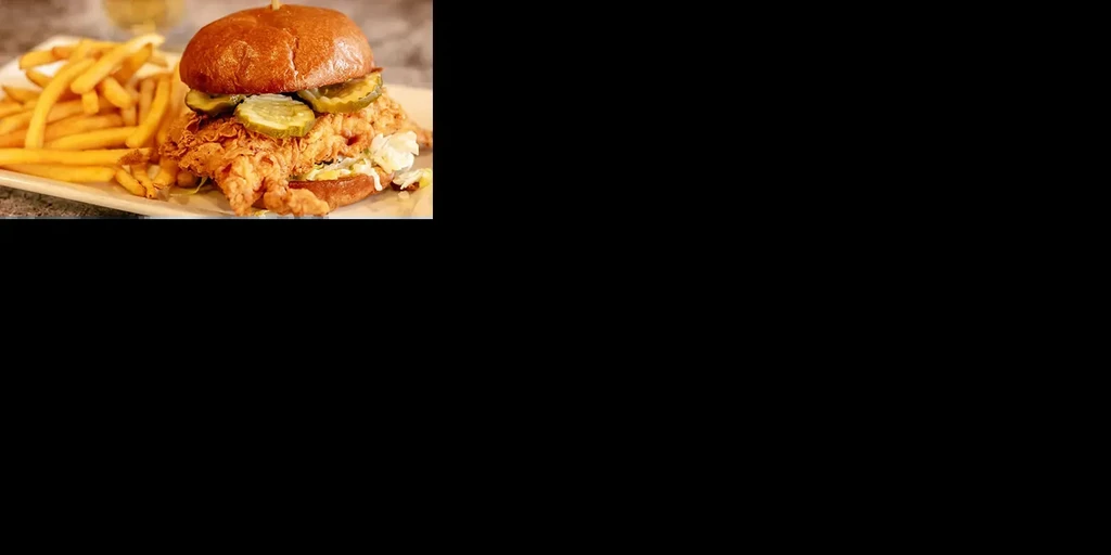 Crispy fried chicken sandwich with pickles, coleslaw, and golden fries.