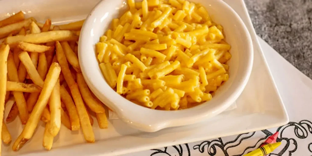 Macaroni and cheese and fries on a plate with crayons.