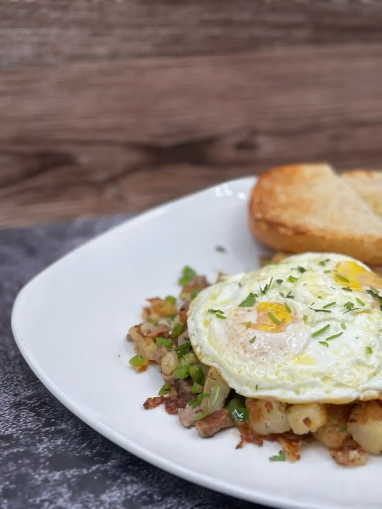 Potato and meat hash topped with two sunny-side up eggs.