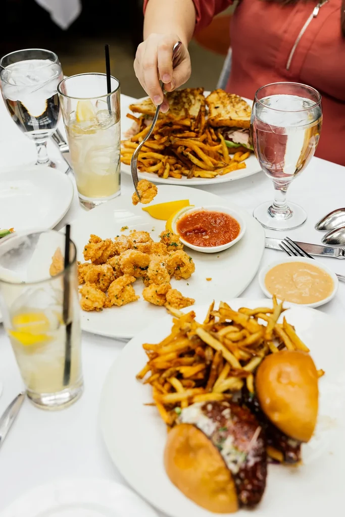Overhead view of a dining table with appetizers, sandwiches, fries, and drinks.