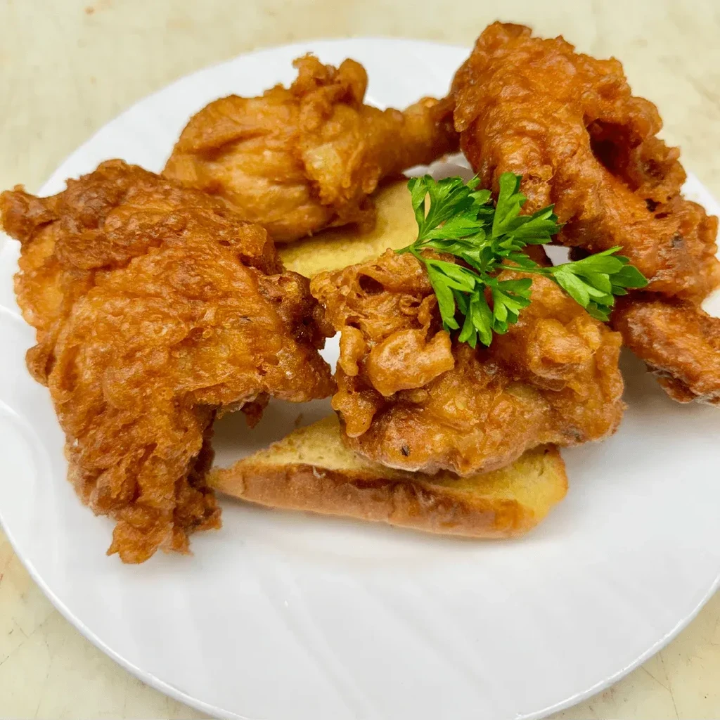 Crispy, golden-brown fried chicken pieces with parsley on a white plate.