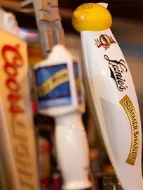 Leinie's Summer Shandy tap handle with lemon top, other taps blurred.