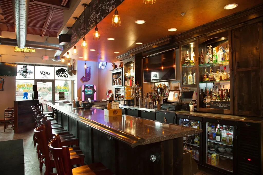 Empty restaurant bar with polished counter and stocked liquor shelves.