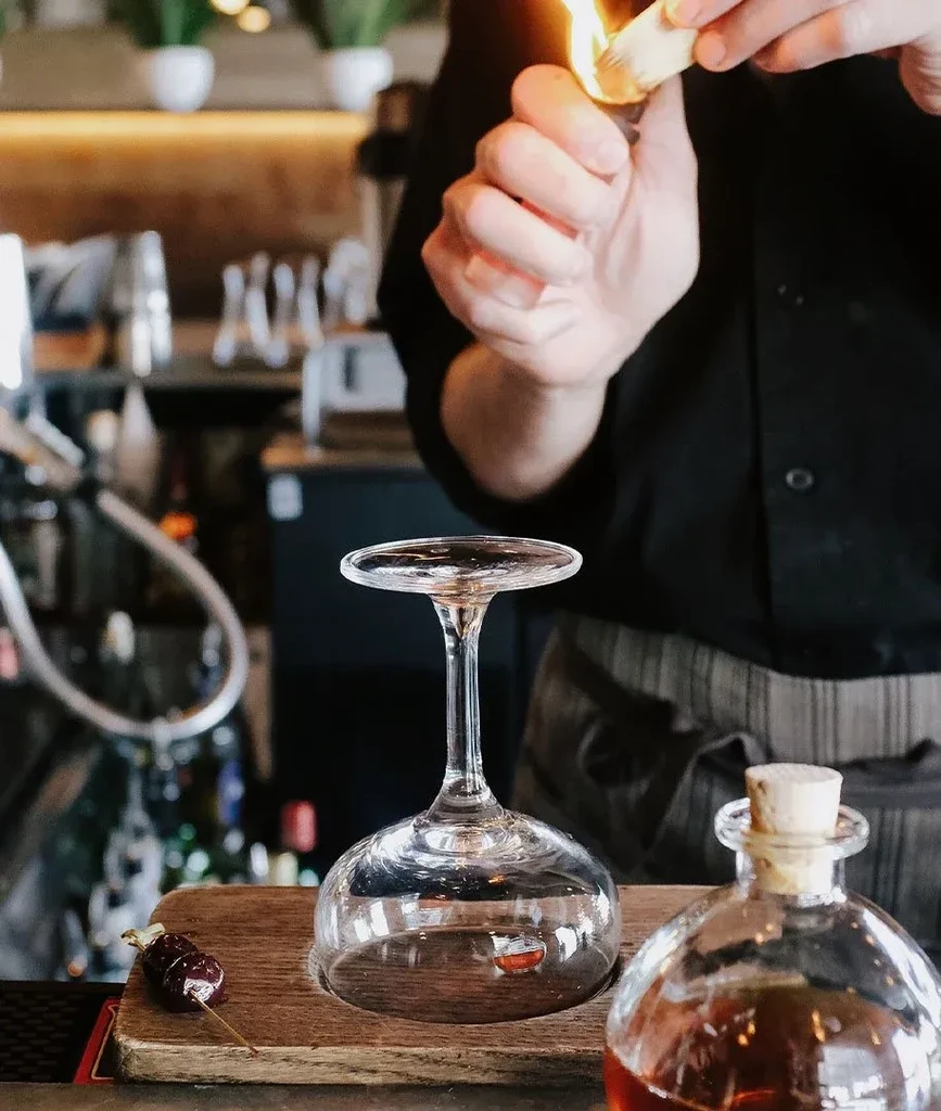 Bartender's hands flame an orange peel for a cocktail.