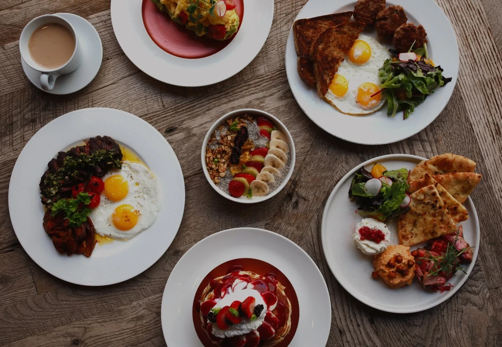 Overhead flat lay of multiple well-plated breakfast and brunch dishes.