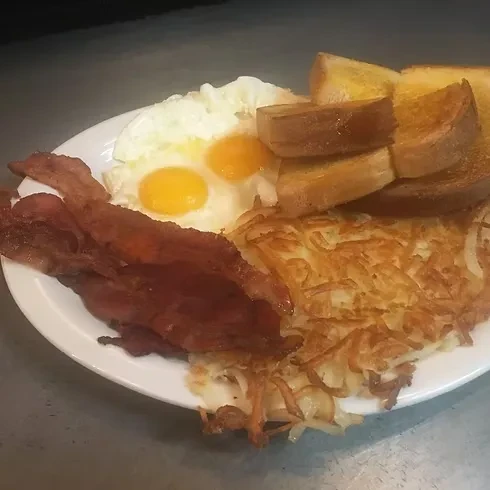 Classic American breakfast plate with bacon, eggs, hash browns, and toast.