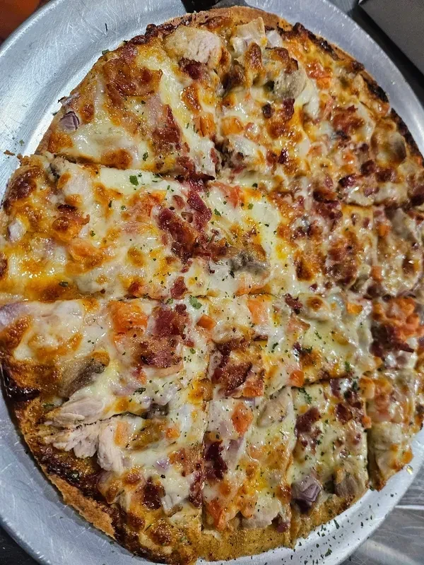 Sliced chicken, bacon, and onion pizza on a metal tray.