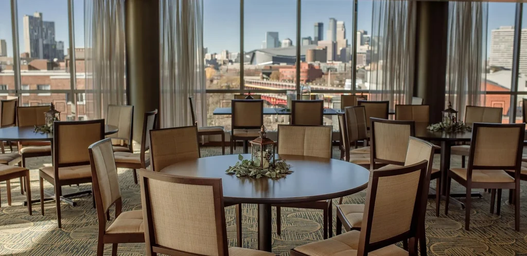 Event room with round tables, lantern centerpieces, and city skyline view.