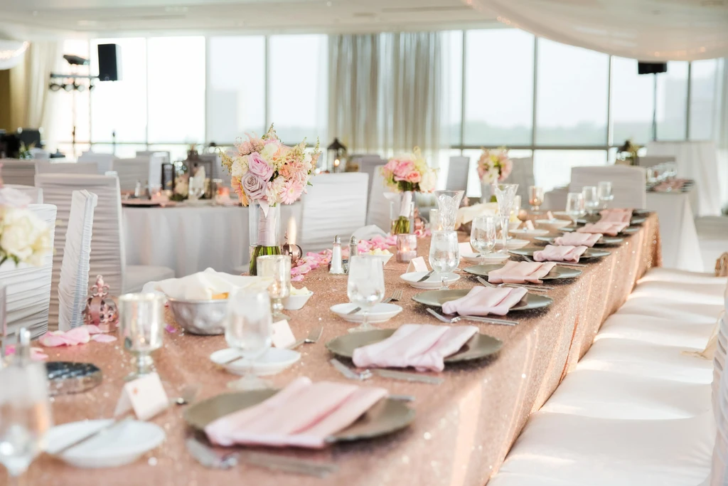 Rose gold sequined dining table with flowers and full place settings.