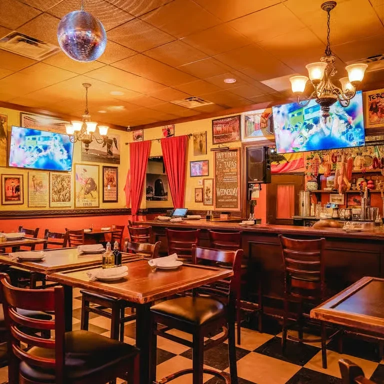 Spanish tapas restaurant interior with bar, dining tables, and disco ball.