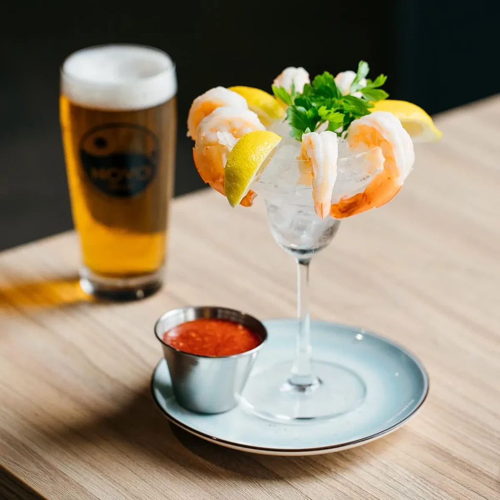 Shrimp cocktail, lemon, cocktail sauce, and a pint of beer.