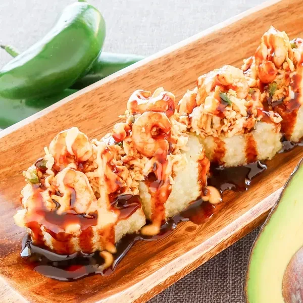 Crispy fried sushi rolls topped with shrimp, sauces, and avocado.