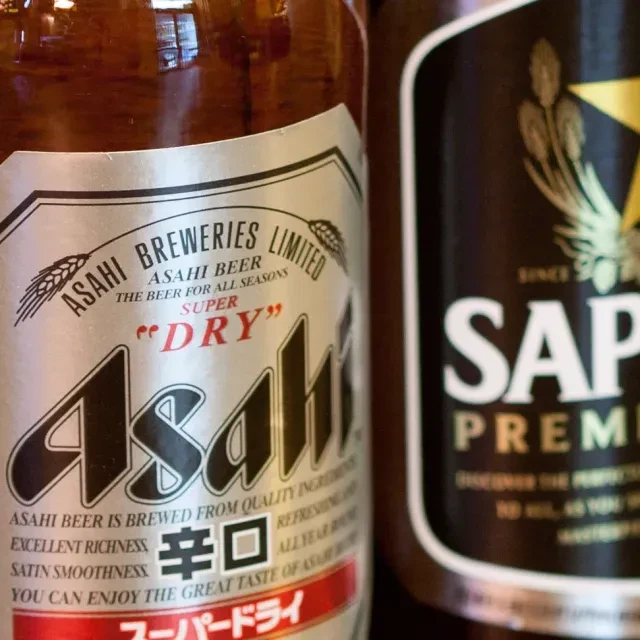 Two beer bottles: Asahi Super Dry in focus, Sapporo Premium blurred.