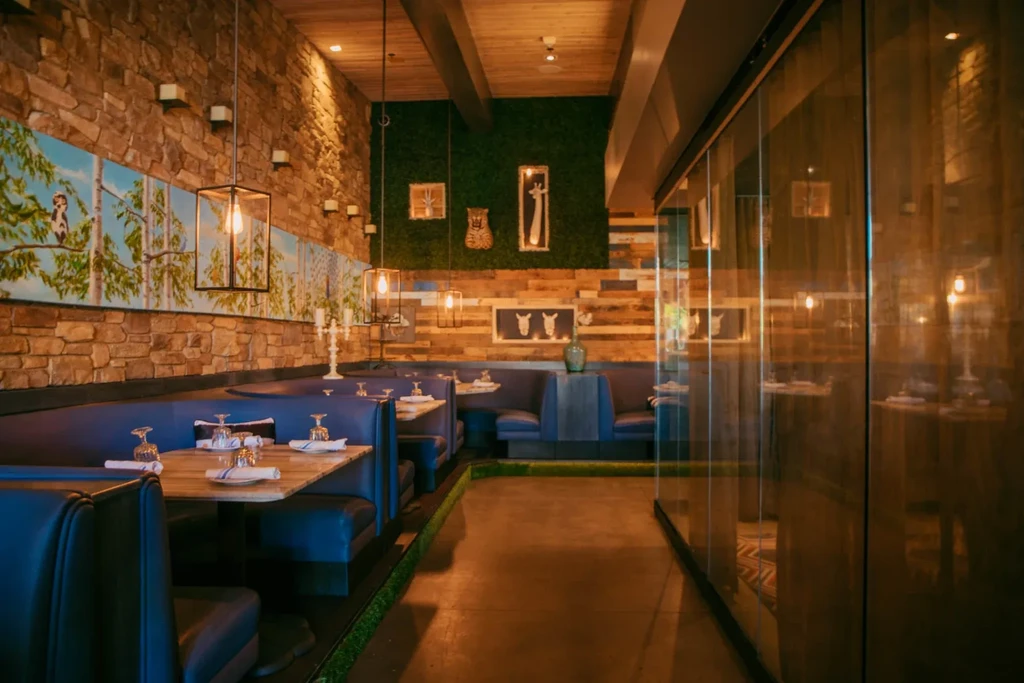 Modern restaurant with navy booths, tree mural, and warm accent lighting.