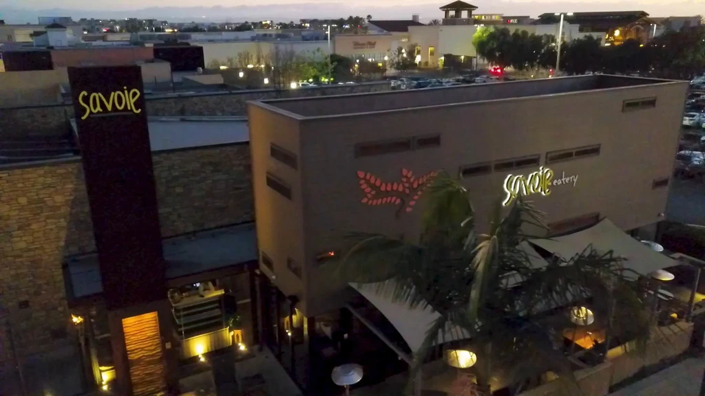 Illuminated Savoie eatery building and outdoor patio at dusk.
