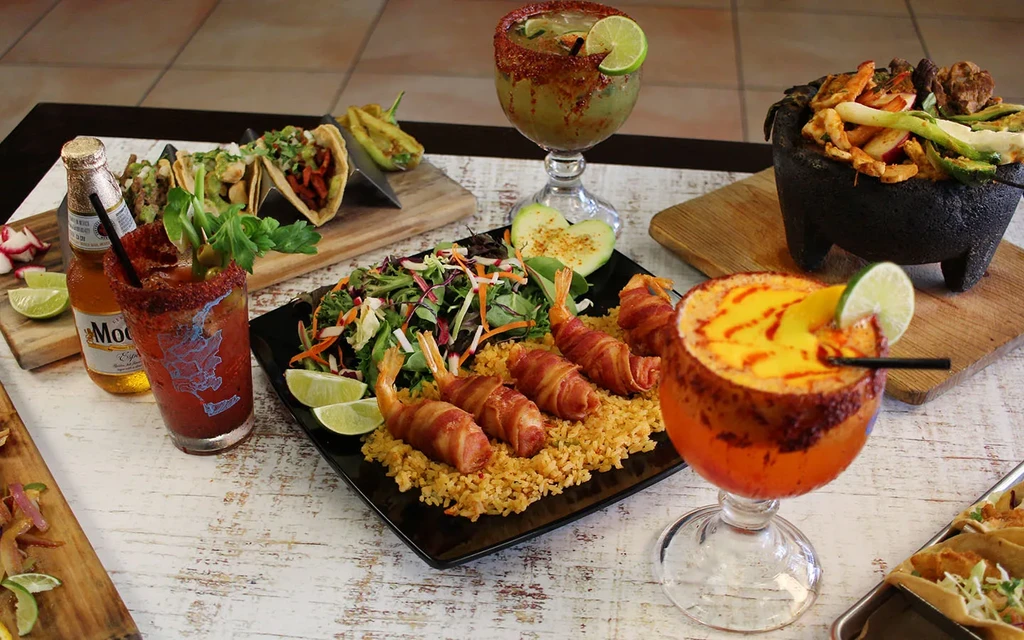 Vibrant spread of Mexican dishes and cocktails on a rustic wooden table.