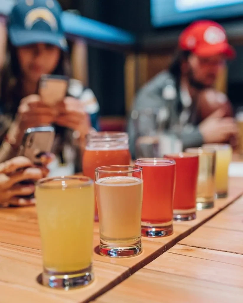 Flight of six colorful beverages on a rustic wooden table.