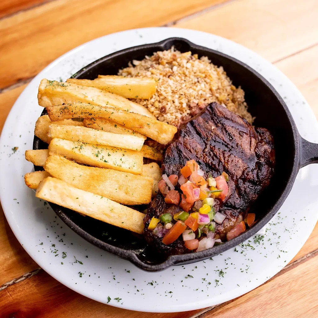 Overhead skillet meal: Steak with pico, fries, and granular side.