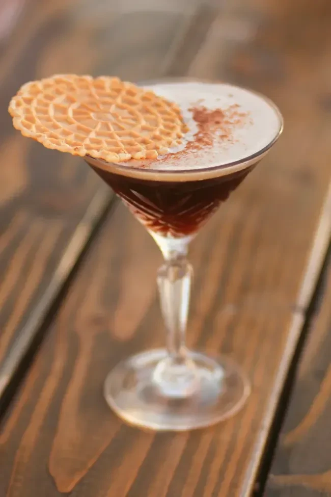 Martini cocktail with foam, dusting, and pizzelle cookie garnish.