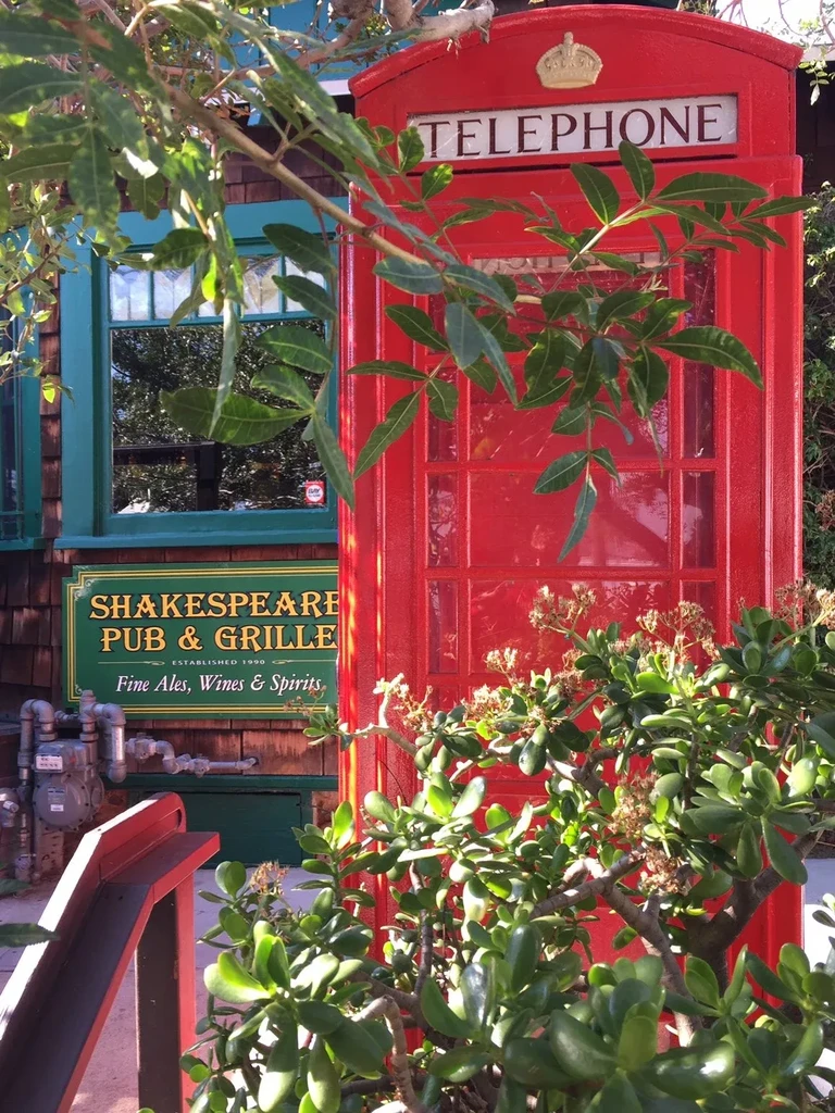 Red British telephone booth next to Shakespeare Pub exterior.
