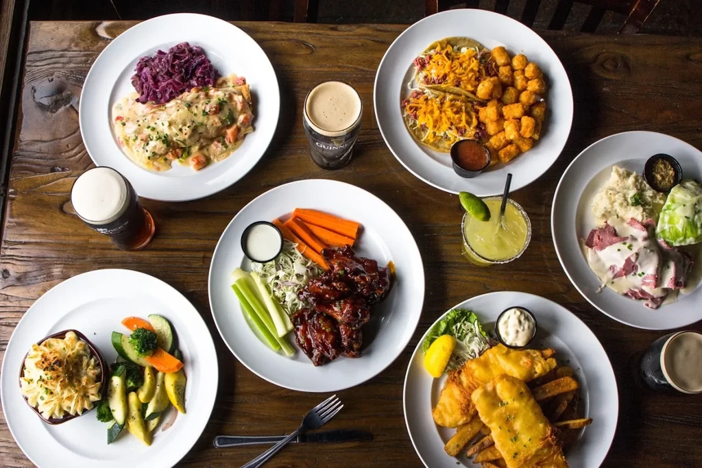 Rustic table laden with various pub dishes and drinks.