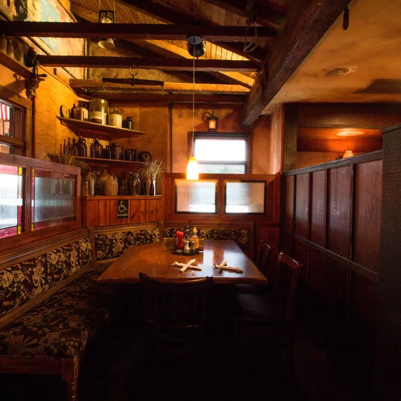 Dimly lit rustic restaurant booth with dark wood and an accessibility symbol.