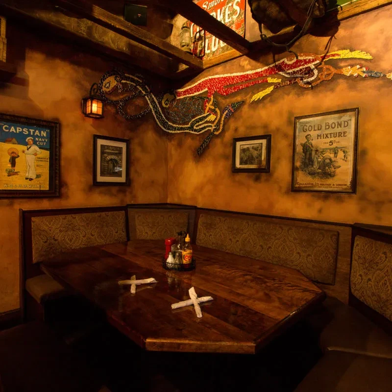 Warm pub booth with octagonal table, condiments, and mosaic creature art.