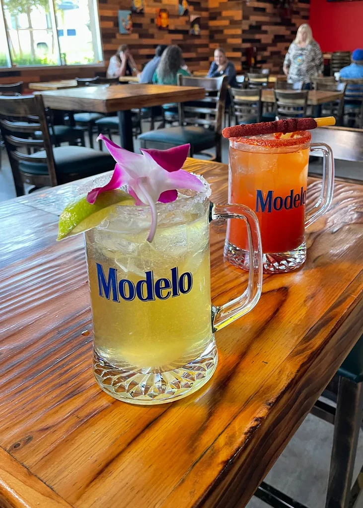 Two colorful Modelo cocktails with lime and chamoy garnishes.