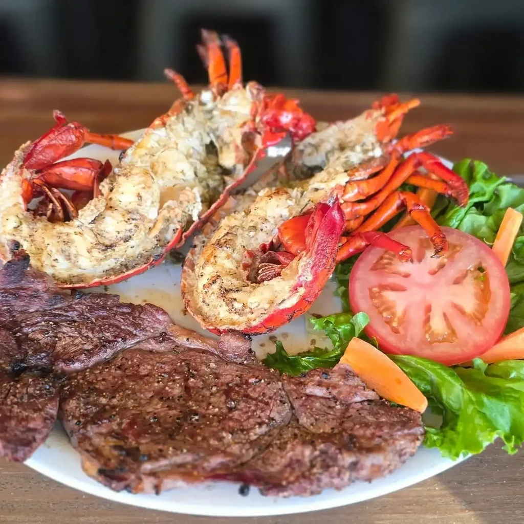 Grilled lobster and steak surf-and-turf with a fresh side salad.