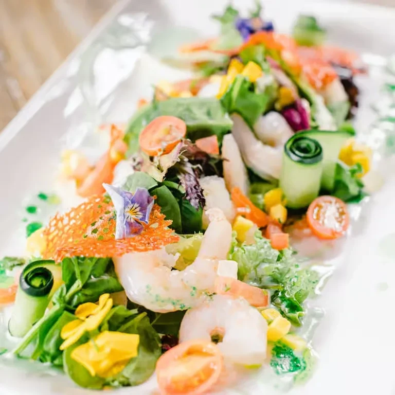 Vibrant salad with cooked shrimp, mango, cucumber, and edible flowers.