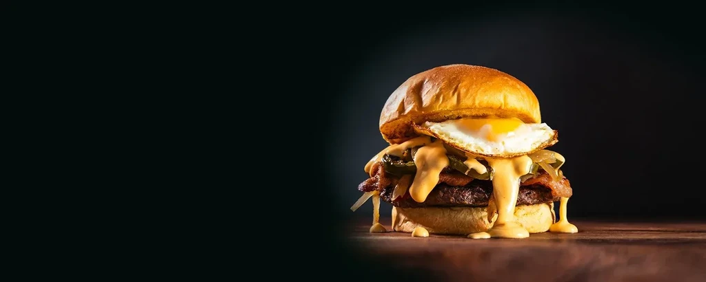 Gourmet burger with two patties, cheese, bacon, and a fried egg.