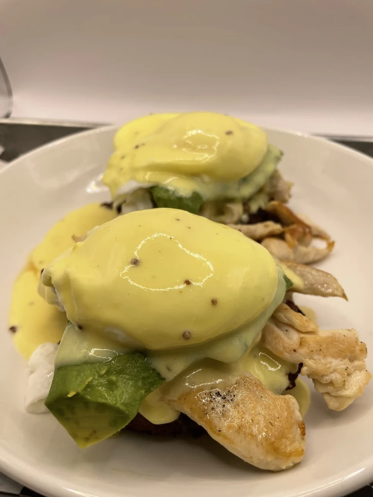 Two chicken and avocado Eggs Benedict with poached eggs and hollandaise.