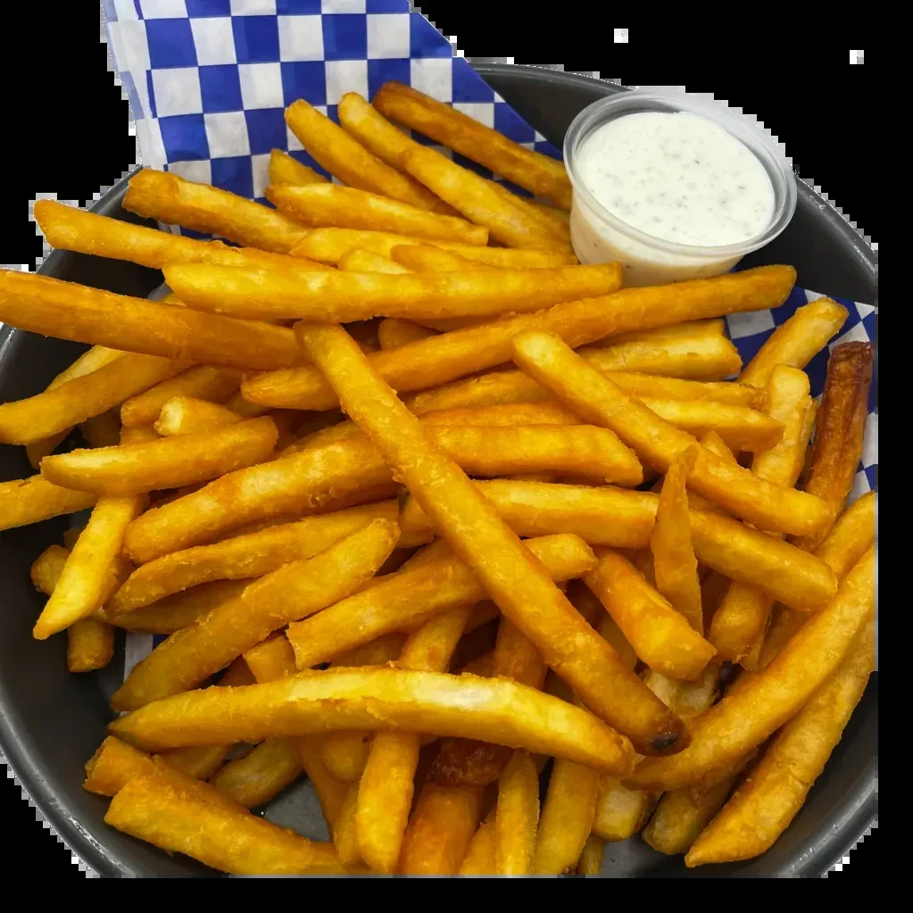 Basket of golden french fries with blue checkered paper and creamy dip.