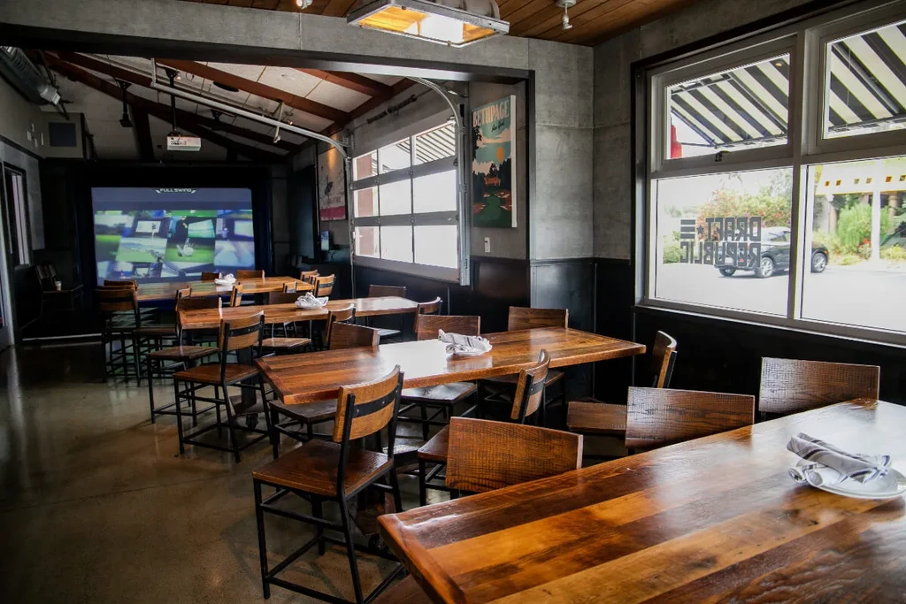 Rustic-industrial restaurant interior with golf simulator and Draft Republic branding.