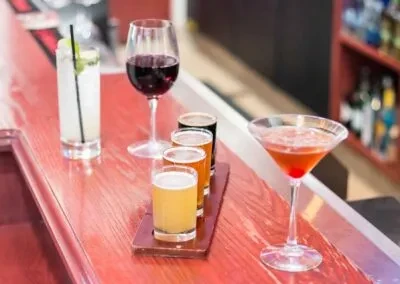 Close-up of cocktails, red wine, and beer flight on a bar.