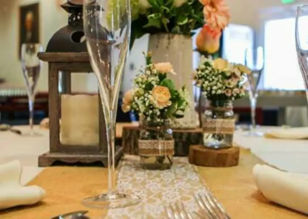 Elegant dining table with floral arrangements, champagne flute, and rustic lantern.