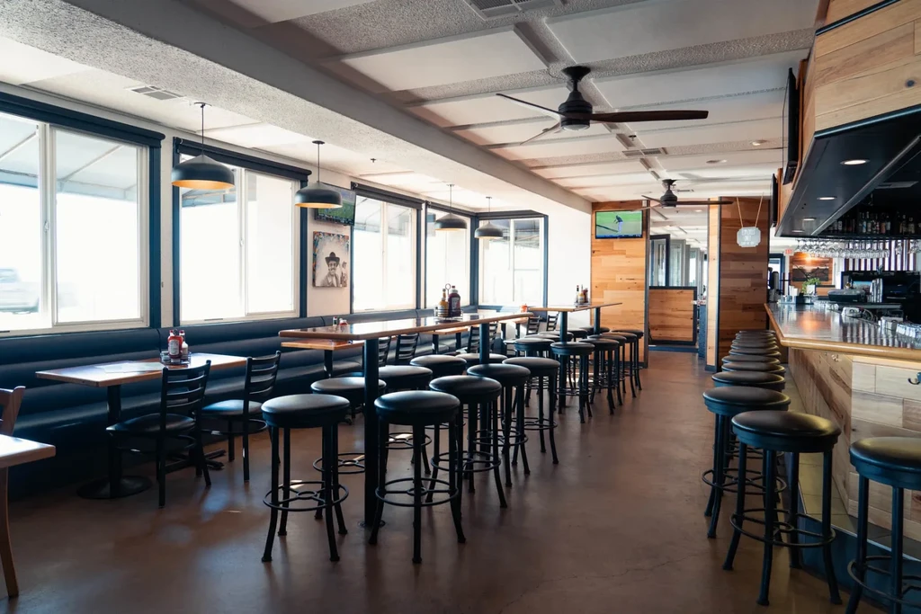 Modern casual restaurant interior with empty dining and stocked bar.