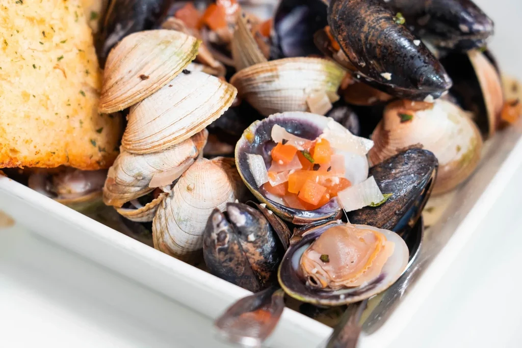 Mussels, clams, and garlic bread in a white rectangular dish.