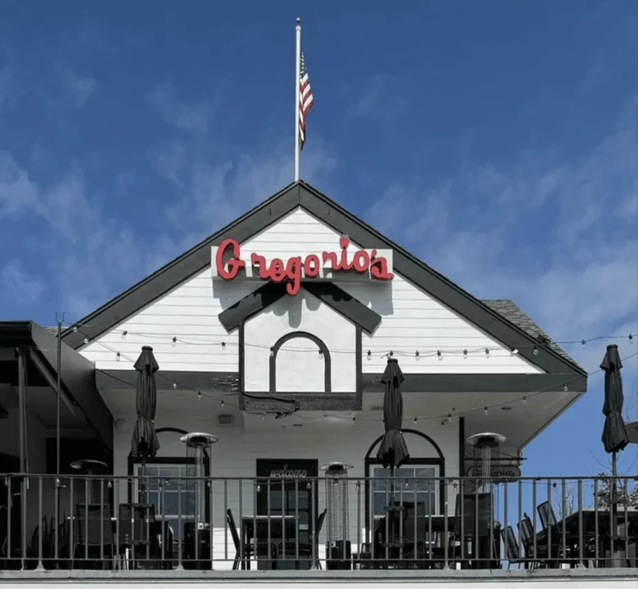 Gregorio's restaurant exterior with white siding, red sign, and outdoor patio.
