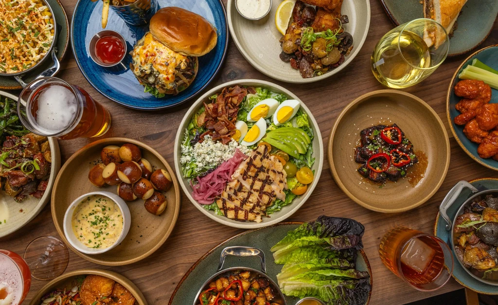Flat lay of diverse food and drinks on a warm wooden table.