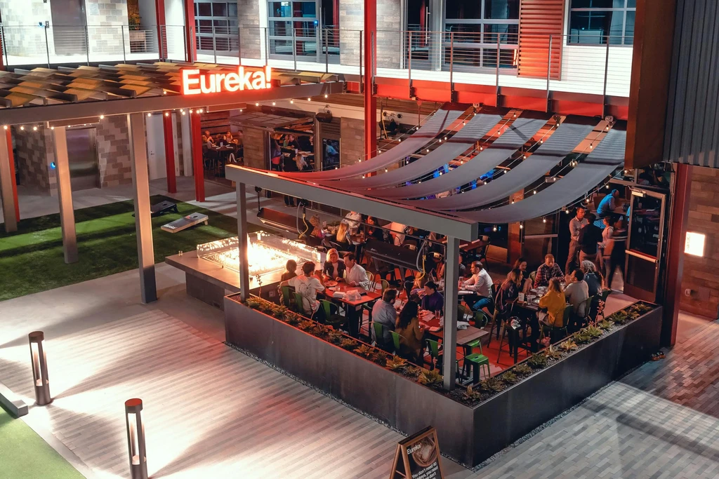 Overhead view of Eureka! outdoor restaurant, fire pit, patrons, cornhole.