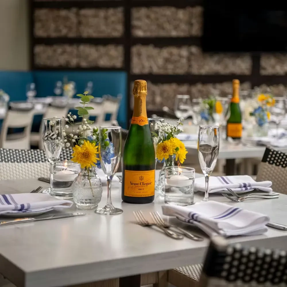 Veuve Clicquot champagne bottle and flutes on an elegant table setting.