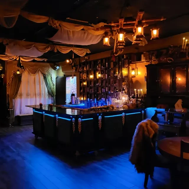 Dark, fantasy-themed bar with blue-lit counter and hanging lanterns.