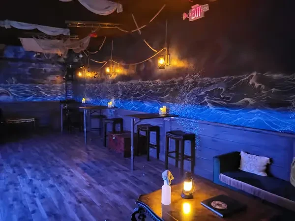Nautical bar interior with glowing ocean mural and warm lantern light.