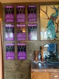 Restaurant wall with nine Wine Spectator awards and a peacock stained glass.