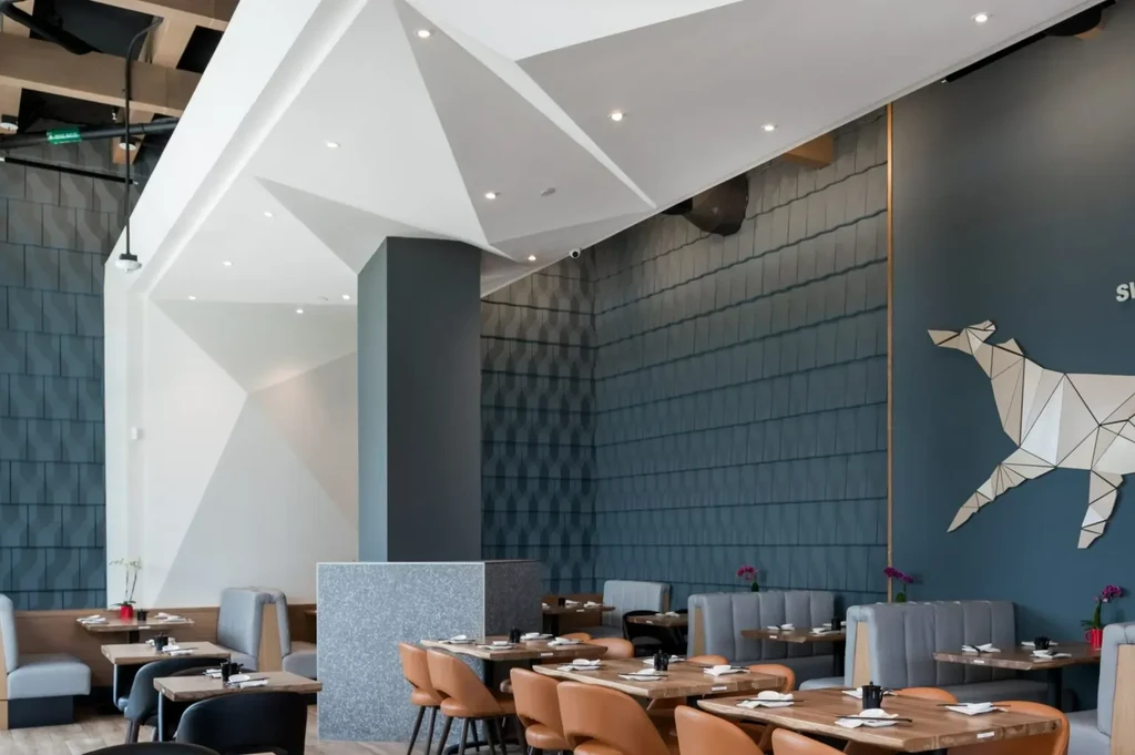 Empty modern restaurant dining room with geometric dog art and set tables.