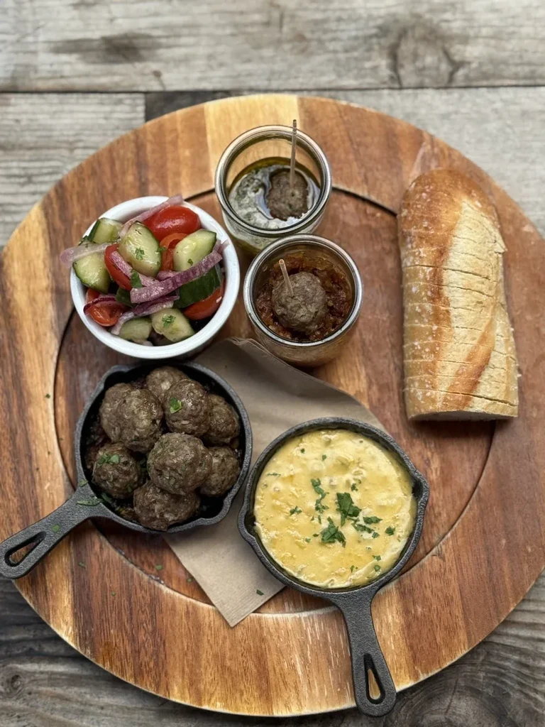 Overhead view of various appetizers, meatballs, and bread on a wooden board.