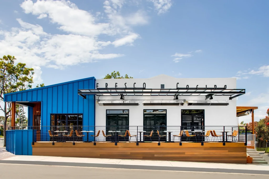 Modern Fresco Cocina with blue siding, white facade, and elevated patio.