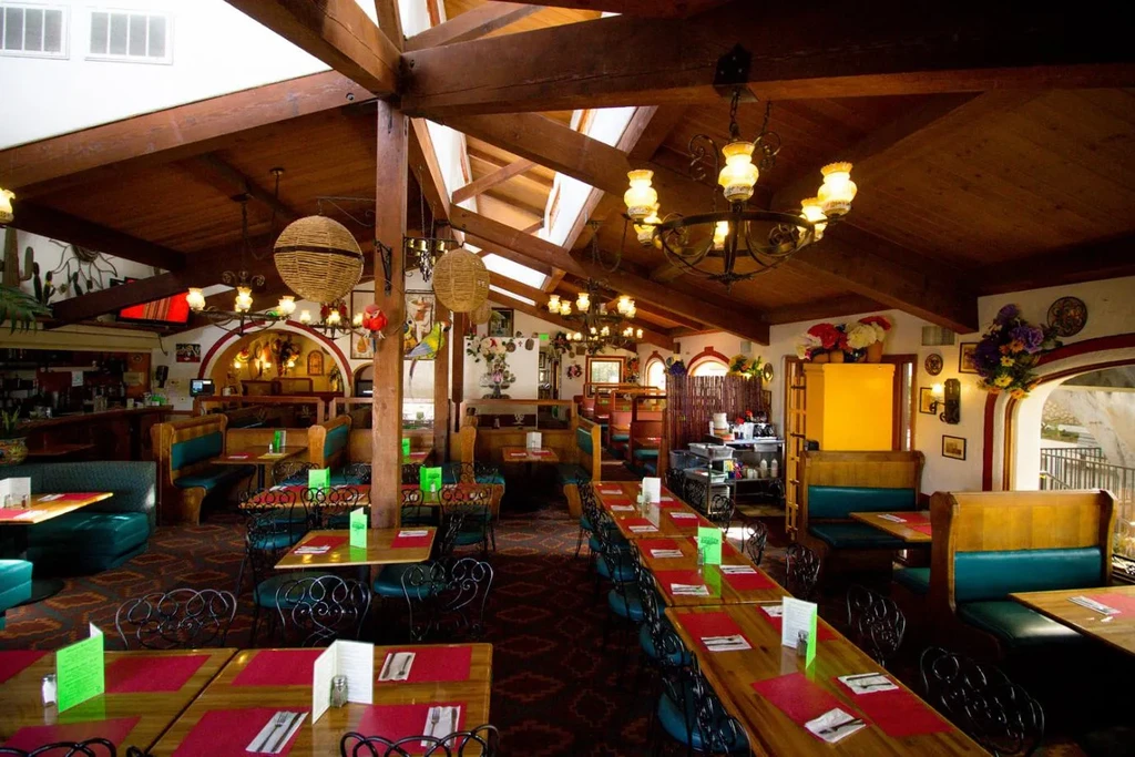 Empty, vibrant Mexican-style restaurant interior with colorful art and rustic decor.